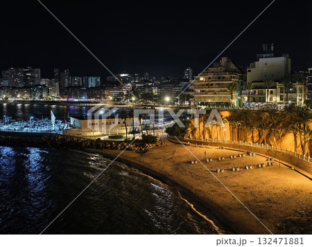 nighttime promenade with glowing reflections, warm lamplight caresses wet sidewalk during calm night 132471881