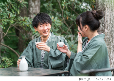 旅館のガーデンテラスの席で日本酒をお酌する浴衣姿のカップル,夫婦 132472063
