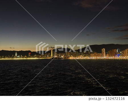 seaside evening reflections, calm coastal panorama during sunset with vibrant promenade illumination seaside evening reflections, calm coastal panorama during sunset with vibrant promenade illumination 132472116