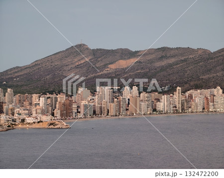 coastal mountain scene, mountains and water surround lively city at dusk with illuminated buildings coastal mountain scene, mountains and water surround lively city at dusk with illuminated buildings 132472200