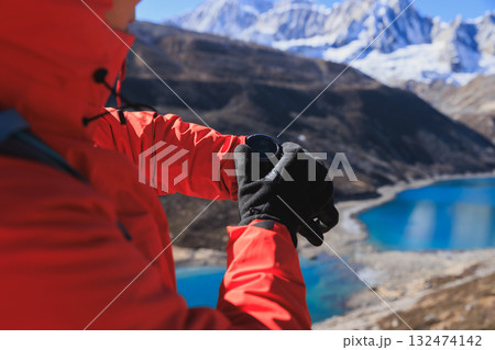 Backpacking woman set the sports watch on high altitude mountain top Backpacking woman set the sports watch on high altitude mountain top 132474142
