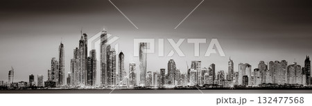 Urban city skyline with illuminated skyscrapers and waterfront railing in black and white at night, Dubai Marina bay UAE 132477568
