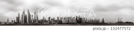 Monochrome city skyline with tall skyscrapers reflecting on calm water under a cloudy sky, Dubai Marina bay UAE Monochrome city skyline with tall skyscrapers reflecting on calm water under a cloudy sky, Dubai Marina bay UAE 132477572