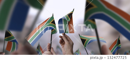 South Africa flags in their hands on a blurred urban background South Africa flags in their hands on a blurred urban background 132477725