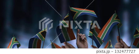 South Africa flags in their hands on a blurred urban background South Africa flags in their hands on a blurred urban background 132477727