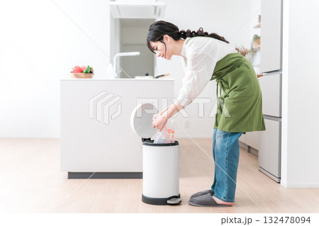 キッチンでゴミ箱のゴミをまとめるエプロン姿の女性,主婦 132478094