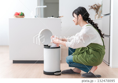 キッチンでゴミ箱のゴミをまとめるエプロン姿の女性,主婦 132478095