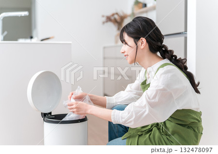 キッチンでゴミ箱のゴミをまとめるエプロン姿の女性,主婦 132478097