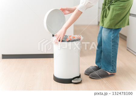 キッチンでゴミ箱のゴミをまとめるエプロン姿の女性,主婦 132478100
