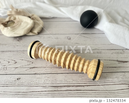 足ケア用品。木製のローラーと黒いボール、バレエシューズがシャビーな床の上に置かれている。 132478334