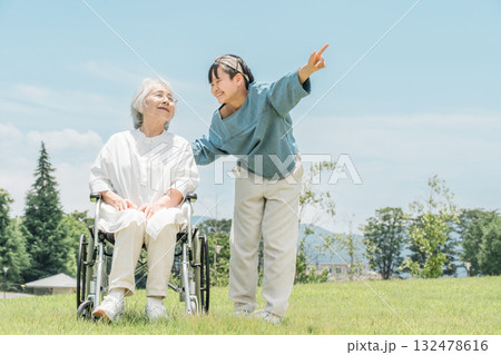 車椅子に乗るおばあちゃんをお見舞い,散歩に来た孫娘 132478616