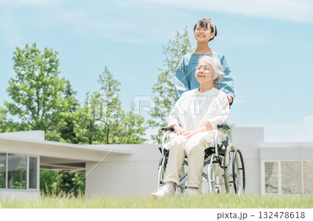 車椅子に乗るおばあちゃんをお見舞い,散歩に来た孫娘 132478618