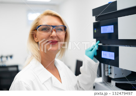 Portrait of scientist next to HPLC system in modern laboratory.  132479497