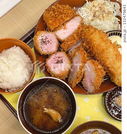 Crispy tonkatsu, a Japanese-style breaded and deep-fried pork cutlet, served with shredded cabbage and drizzled with savory sauce. A delightful balance of crunchy texture and juicy meat. 132479643