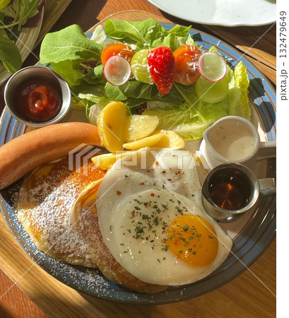 Fluffy soufflé pancake topped with airy cream, sweet banana slices, and juicy peaches, offering a perfect blend of soft texture and fruity sweetness in every dreamy, melt-in-your-mouth bite. 132479649