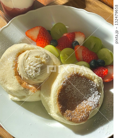 Fluffy soufflé pancake topped with airy cream, sweet banana slices, and juicy peaches, offering a perfect blend of soft texture and fruity sweetness in every dreamy, melt-in-your-mouth bite. 132479658