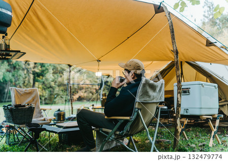 秋冬のキャンプ場でタープの下でコーヒーを飲む男性キャンパー 秋冬のキャンプ場でタープの下でコーヒーを飲む男性キャンパー 132479774