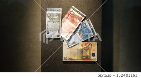 Four euro banknotes on a panel, arranged like playing cards. 132481163