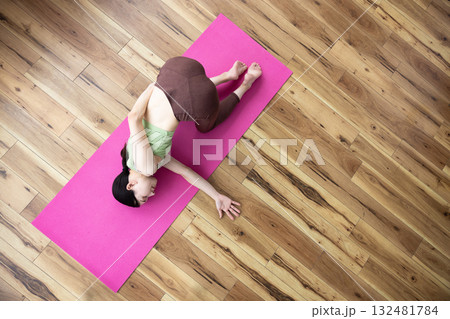 ヨガマットの上で肩を伸ばすポーズをする女性 ヨガマットの上で肩を伸ばすポーズをする女性 132481784