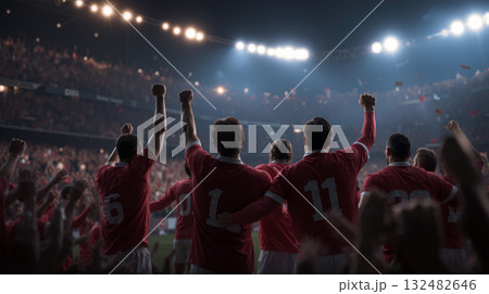 Soccer team celebrates a thrilling goal under bright stadium lights with cheering fans in the background during a competitive match 132482646