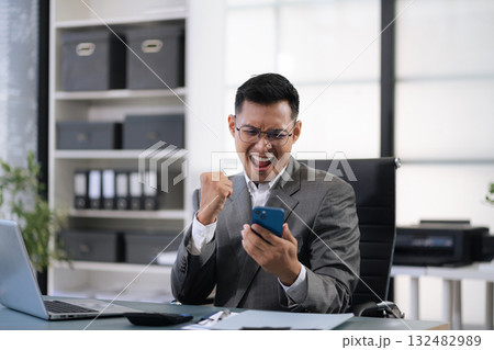 Happy young male use laptop feel euphoric overjoyed triumph with good news over smartphone call. Happy young male use laptop feel euphoric overjoyed triumph with good news over smartphone call. 132482989