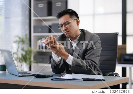 Male businessman is doing a stretchy posture due to sitting in the office for too long, office syndrome concept. 132482998