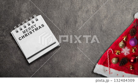 Greeting of Merry Christmas text in a notepad on a black background. Mockup or Copy space. Holiday greetings or winter themes. Concept of the Merry Christmas celebration Greeting of Merry Christmas text in a notepad on a black background. Mockup or Copy space. Holiday greetings or winter themes. Concept of the Merry Christmas celebration 132484309