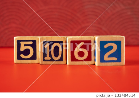 Row of wooden number blocks with various numbers on a red background 132484314