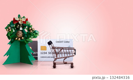 Shopping cart with credit card and Christmas tree ornament on colored background. Copy space. Christmas sale concept Shopping cart with credit card and Christmas tree ornament on colored background. Copy space. Christmas sale concept 132484316