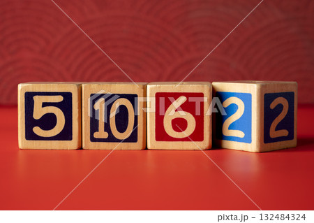 Row of wooden number blocks with various numbers on a red background Row of wooden number blocks with various numbers on a red background 132484324