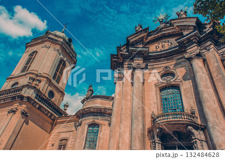 The image shows a baroque architectural style building which appears to be a church or cathedral. We can see its ornate facade with statues, decorative moldings, and a Latin inscription. The church 132484628