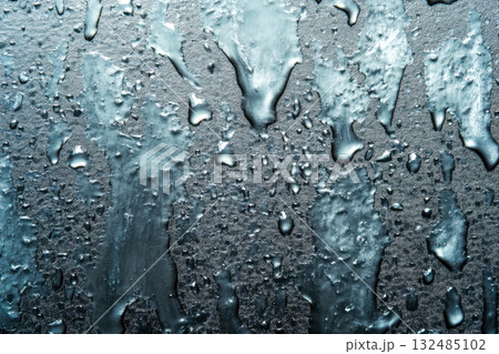Raindrops are seen on a smooth surface, creating a glistening effect as light reflects off the wet texture during a rainy day Raindrops are seen on a smooth surface, creating a glistening effect as light reflects off the wet texture during a rainy day 132485102