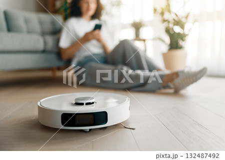 White robotic vacuum cleaner on wooden floor 132487492