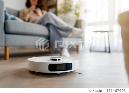 White robotic vacuum cleaner on wooden floor 132487493