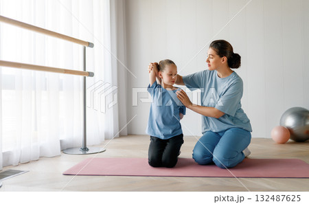girl doing exercises under doctor's supervision girl doing exercises under doctor's supervision 132487625