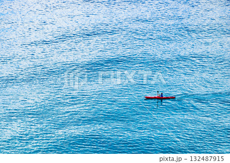 Person kayaking on blue sea. Person kayaking on blue sea. 132487915