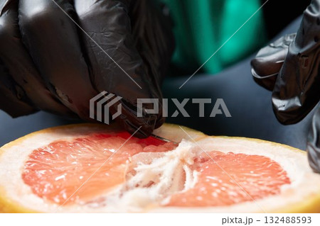 Half of grapefruit with vertical barbell piercing on a background. 132488593