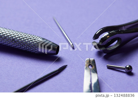 Piercing earrings close-up. On a Violet background. 132488836