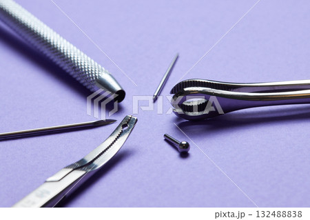 Piercing earrings close-up. On a Violet background. 132488838