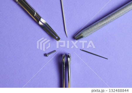 Piercing earrings close-up. On a Violet background. 132488844