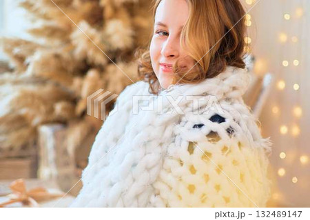 teenage girl in a dress near an unconventional Christmas tree surrounded by golden lights 132489147