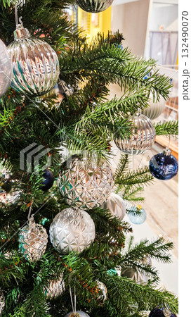 A decorated Christmas tree with various ornaments. The tree features green branches adorned with blue and silver baubles, creating a festive atmosphere. A decorated Christmas tree with various ornaments. The tree features green branches adorned with blue and silver baubles, creating a festive atmosphere. 132490070