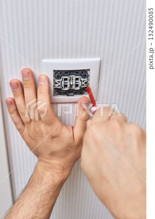 electrician working on light switch using screwdriver inside, close-up electrician working on light switch using screwdriver inside, close-up 132490085