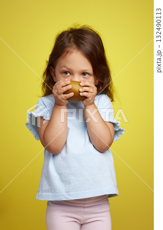 cute Caucasian little child girl holding kiwi fruit on yellow background cute Caucasian little child girl holding kiwi fruit on yellow background 132490113