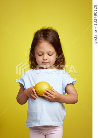 cute Caucasian little child girl holding lemon on yellow background cute Caucasian little child girl holding lemon on yellow background 132490129