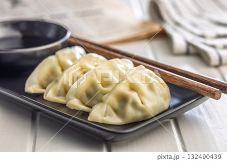 Traditional japanese gyoza dumplings on plate on white table. Traditional japanese gyoza dumplings on plate on white table. 132490439