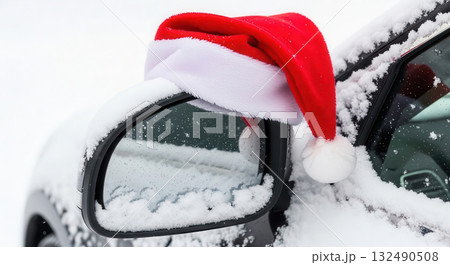 Red Santa hat resting on a snowy car mirror, surrounded by a winter wonderland, capturing the festive spirit of Christmas and New Year celebrations with holiday cheer 132490508
