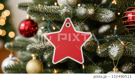 Red star-shaped tag hanging on a Christmas tree adorned with ornaments and lights, creating a festive atmosphere for holiday celebrations and New Year discounts Red star-shaped tag hanging on a Christmas tree adorned with ornaments and lights, creating a festive atmosphere for holiday celebrations and New Year discounts 132490511