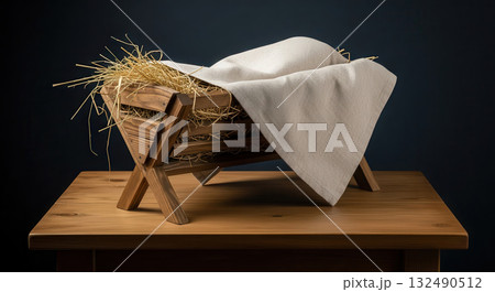 Wooden manger with straw and white cloth, symbolizing Christmas spirit, set on a rustic wooden table, evoking warmth and holiday traditions in a serene atmosphere Wooden manger with straw and white cloth, symbolizing Christmas spirit, set on a rustic wooden table, evoking warmth and holiday traditions in a serene atmosphere 132490512