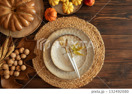 Festive Autumn Table Setting with Ceramic Plates, Pumpkins, Cake and Rustic Decor 132492080